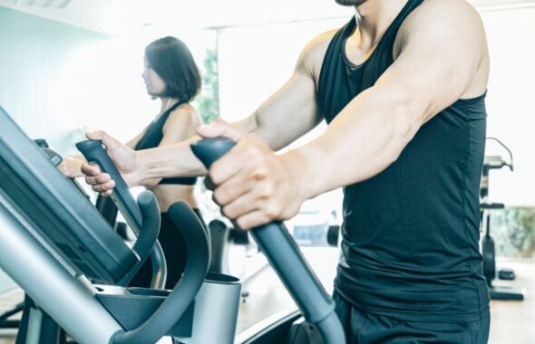 パーソナルジムで有酸素マシンを使ってトレーニングを行う男女の写真