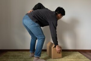 荷物を取るときに腰痛が出れいる男性