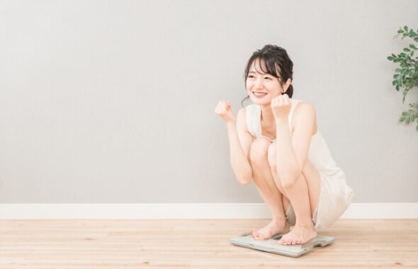 ダイエットの成果を図るために体重計に乗る女性