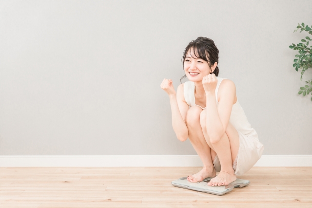 ダイエットの成果を図るために体重計に乗る女性