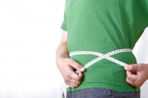 食事制限ダイエット成果の確認でウエストを図る男性