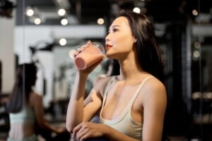 トレーニング終わりに栄養補給としてプロテインを飲む女性
