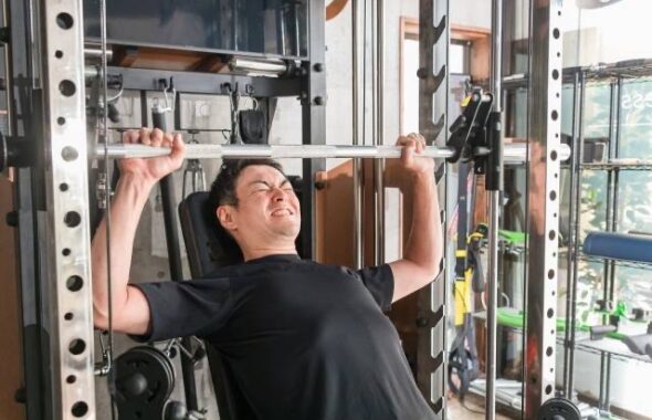 トレーニングジムでショルダープレスをしている男性