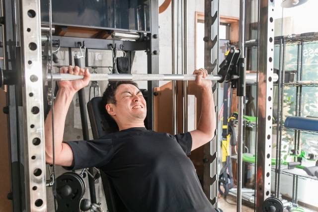トレーニングジムでショルダープレスをしている男性
