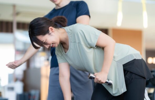 パーソナルトレーナーの指導の元背中のトレーニングを行う女性