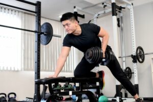 パーソナルトレーニングジムでワンハンドロウをしている男性